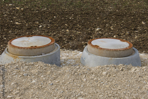 Kanalisation und Kanaldeckel aus Beton / Wasserleitung in einem Neubaugebiet (Hauswasseranschluss / Erschließung und Versorgung)