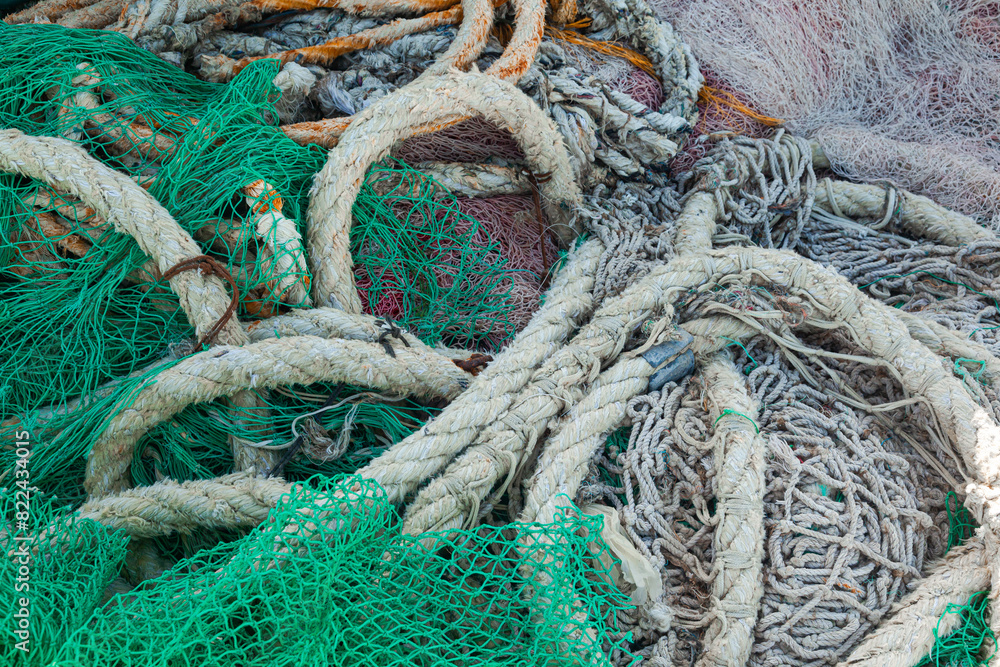 There is a large pile of fishing nets lying on the wooden pier to dry.