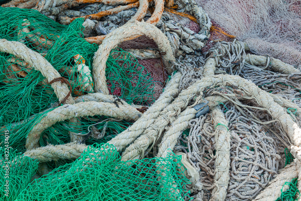 There is a large pile of fishing nets lying on the wooden pier to dry. There is a large pile of fishing nets lying on the wooden pier to dry.