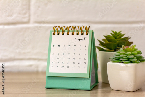 Desktop calendar for August 2024. Monthly planning calendar and vase with dried flowers on the table.