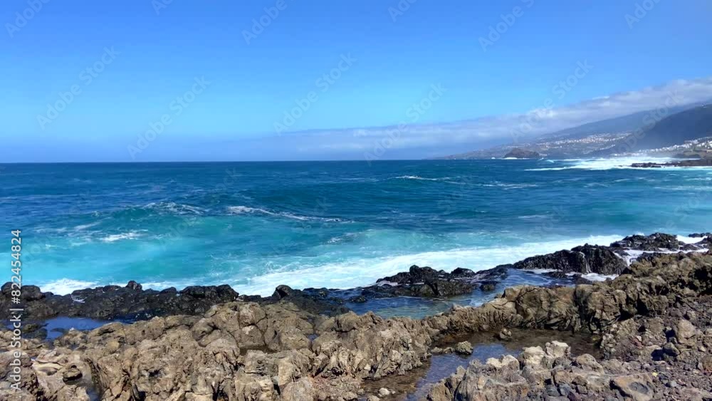 Big waves splash against black lava rock and blue Atlantic Ocean near Los Silos, Tenerife, Canary islands, Spain. Sunny spring day. Big waves splash against black lava rock and blue Atlantic Ocean near Los Silos, Tenerife, Canary islands, Spain. Sunny spring day.