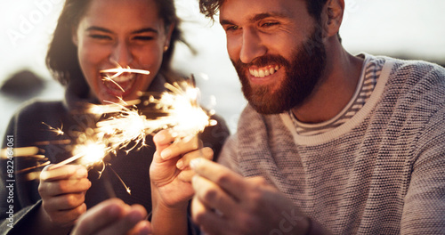 Happy, couple and fireworks sparkle at celebration with happiness on holiday or vacation in summer. Fire, sparks and people excited for countdown to new year at party or event outdoor with glow stick photo