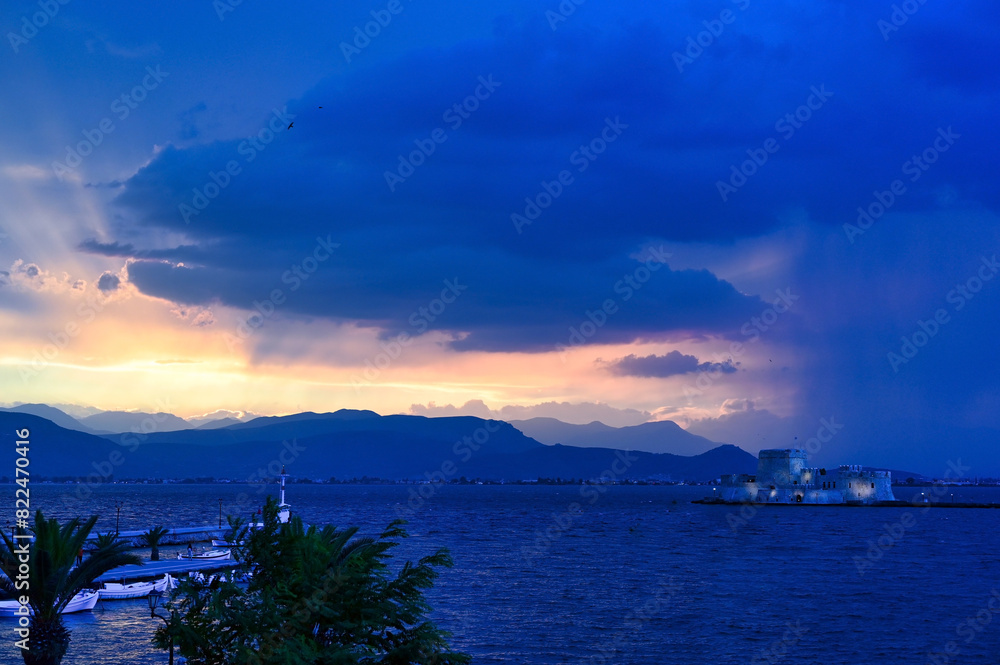 Stormy sky and sunset over Bourtzi water fortress in Nafplio, Peloponnese, Greece
