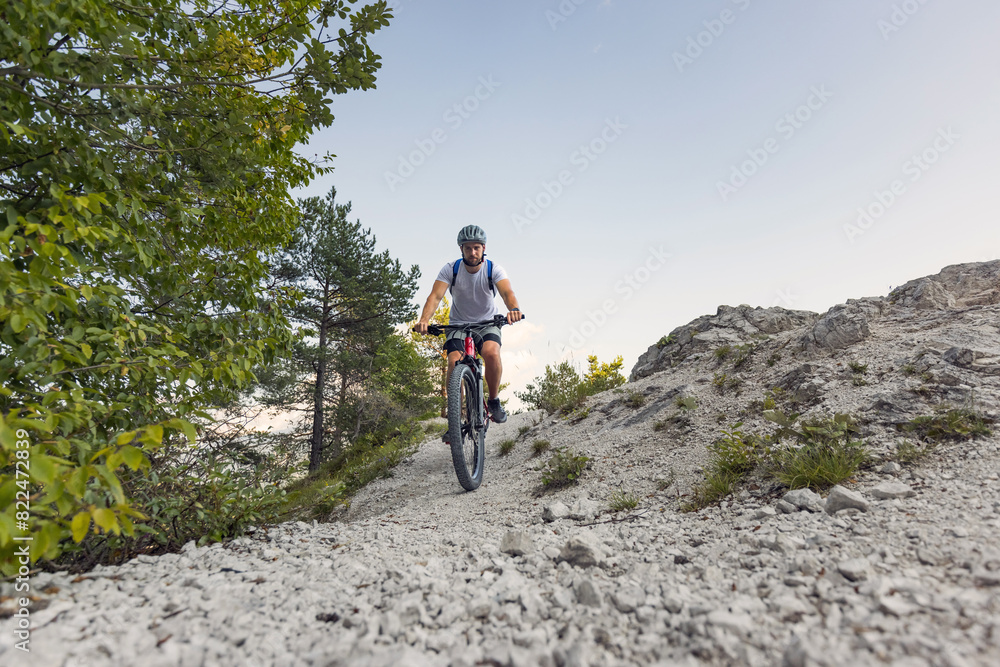 Recreational cyclist riding an electric mountain bike on white gravel path. EMTB cycling concept.