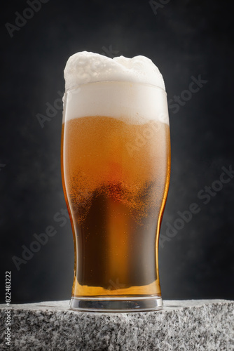 Beer. Pilsner beer in glass on a granite stone. Glass of fresh and cold beer on gray dark background. Selective focus