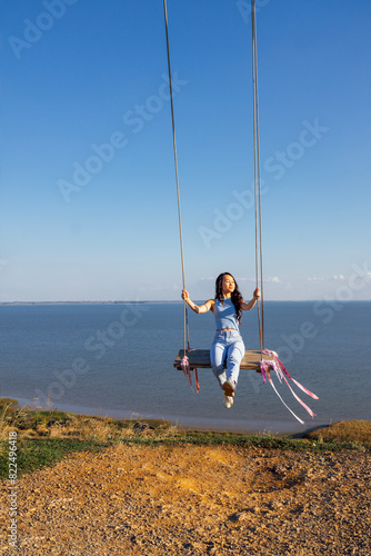 Attractive Asian girl in casual clothes swinging on an outdoor swing
