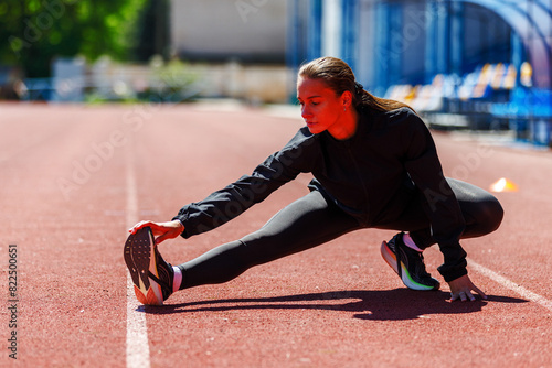 Young fitness sportswoman stretching her legs at the track and field stadium © skumer