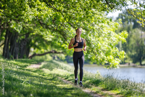 Young fitness woman jogging in park near the river at sunny morning © skumer