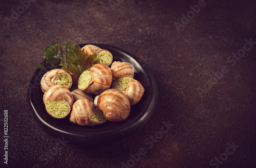 snails stuffed in Burgundy, on a black plate, with grape leaves, French cuisine, no people,