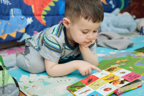 young boy reading a book with animal pictures