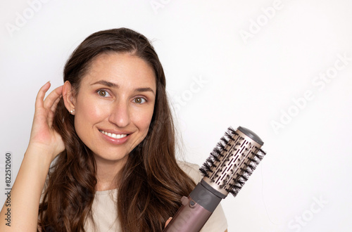 smiling woman using rotative hair brush to arrange or dry hair.isolated girl with beautiful natural hair and dryer in hand. happy satisfied female, advertising banner for care, styling product.