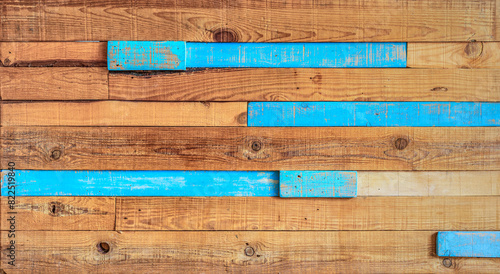 A textured background of a wooden panel made with rustic wooden slats, unpainted wood, and some blue-colored slats.