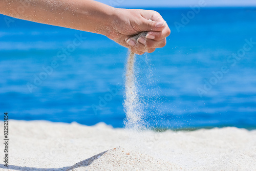 A Hands pour sand off the sea on nature on a journey. Vacations at sea sand time passes.
