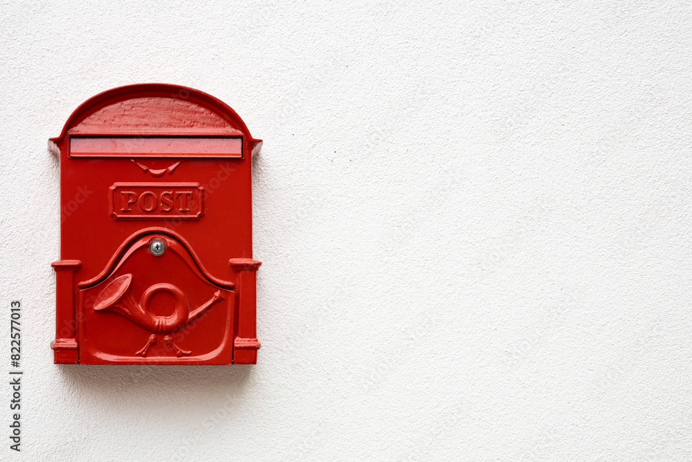 Traditional bright red post box on white plaster texture wall in Hungry. Metal mailbox with text POST in English language. Copy space Traditional bright red post box on white plaster texture wall in Hungry. Metal mailbox with text POST in English language. Copy space