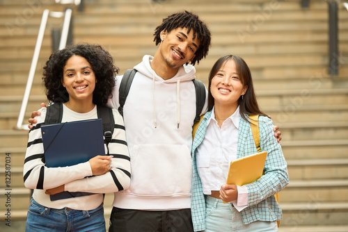 Three young students are smiling and looking to camera