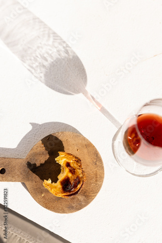 Overhead shot of pastel de nata and red port wine with afternoon shadows in Portugal. photo