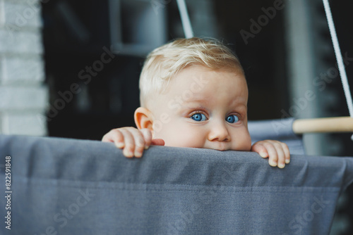 Baby boy swings in a swing at home. The child learns to have fun. Child development.