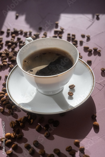 cup of coffee and coffee beans on pink background