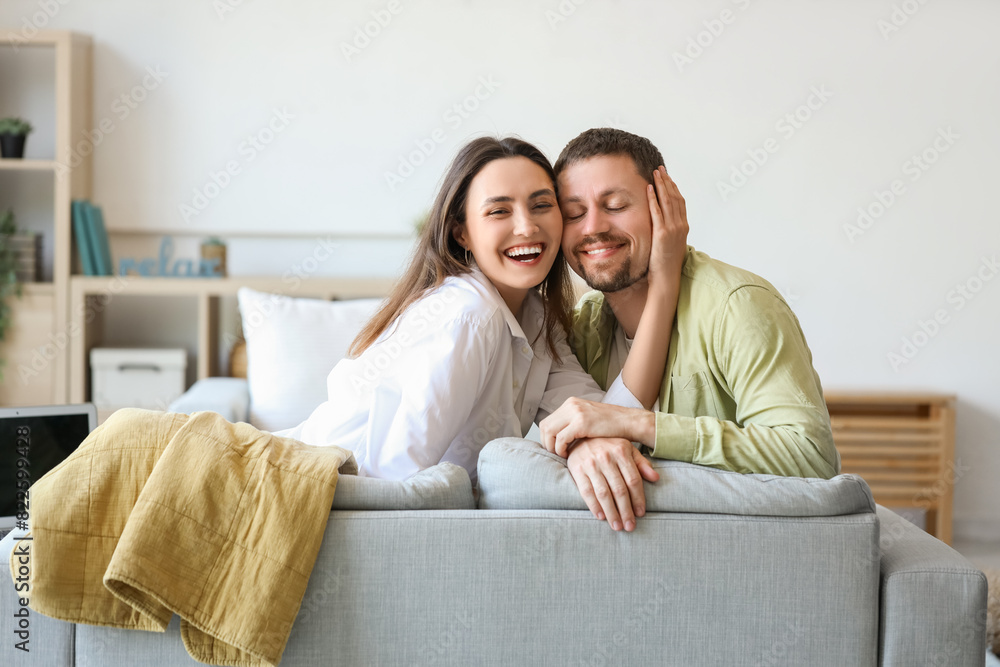 Happy young couple sitting on sofa at home Happy young couple sitting on sofa at home