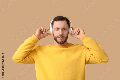 Young man in modern headphones on brown background