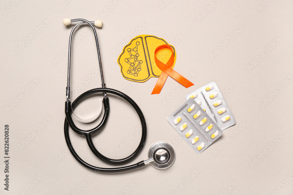 Stethoscope, pills, paper brain and orange ribbon on grey background. Multiple Sclerosis Awareness Month Stethoscope, pills, paper brain and orange ribbon on grey background. Multiple Sclerosis Awareness Month