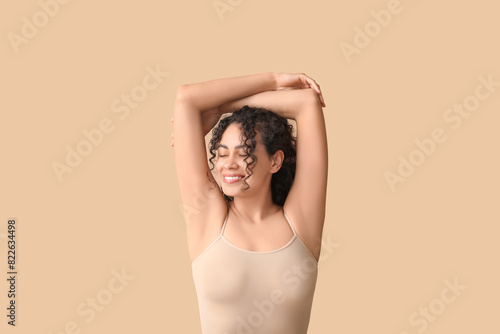 Beautiful young African-American woman on brown background photo