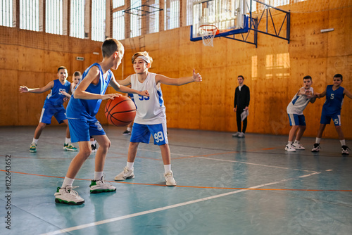 Junior basketball team playing basket on training at indoor court.