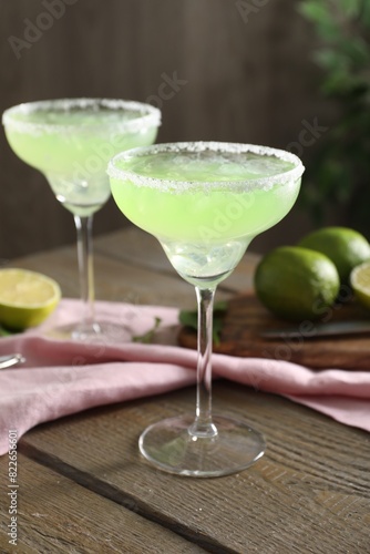 Delicious Margarita cocktail in glasses on wooden table, closeup