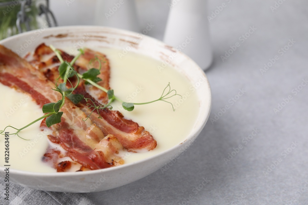 Delicious potato soup with bacon and microgreens on grey table, closeup. Space for text Delicious potato soup with bacon and microgreens on grey table, closeup. Space for text