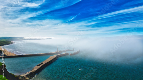 Aerial view of coastal pier with lighthouse and fog in Whitby, North Yorkshire
