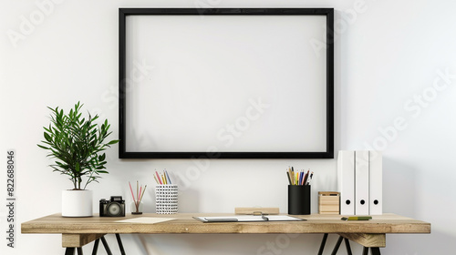 Black frame on a white wall, above a small wooden desk with stylish stationery and a potted plant. © Glenn Finch