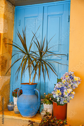 Greece. Blue wall and flower basket with terra cotta pot and flowers photo