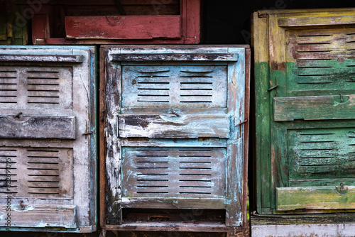 Old beehives in rustic appearance with peeling paint and chipped wood in green, blue in worn and aged look. Reusing and recycling materials, reducing waste and extending lifespan of products