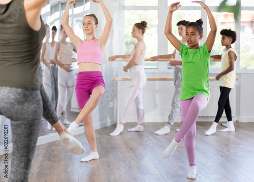 Group of boys and girls teenage dancers rehearsing ballet moves in dance studio
