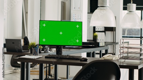 Greenscreen monitor in coworking space running on desk  open floor plan small business office. Computer showing isolated mockup template with blank chromakey screen  modern career.