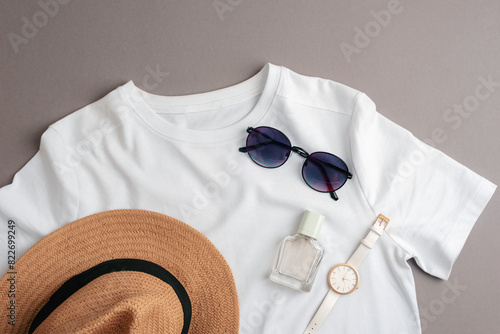 White T-shirt, straw hat, sunglasses, watch and perfume bottle. Overhead view of woman's casual summer outfit. Trendy hipster look. Flat lay