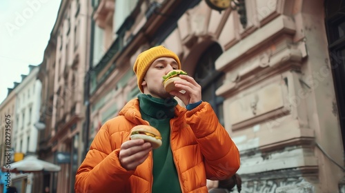 Stylish caucasian man in orange jacket green sweater and yellow hat eats burger on city street of Wroclaw Poland : Generative AI