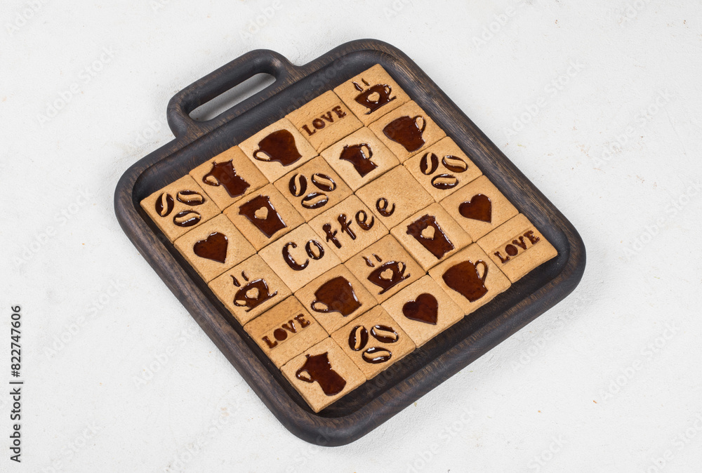 Vegan dessert. Coffee cookies are square with a filling of coffee marmalade in the shape of a cup, heart, coffee pot, coffee beans, the words coffee, love. On a wooden plate. Vegan dessert. Coffee cookies are square with a filling of coffee marmalade in the shape of a cup, heart, coffee pot, coffee beans, the words coffee, love. On a wooden plate.