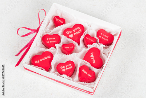 Romantic dessert. Strawberry cream cake in the shape of a heart with thematic inscriptions on top "I love you", "My darling", "Do you love me?", "Kiss me", "I want to meet". In a box
