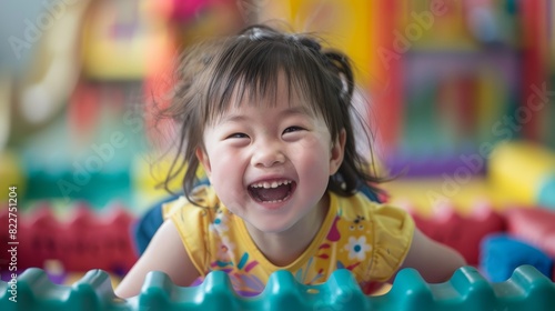 A young girl is smiling and laughing while laying on a colorful plastic mat