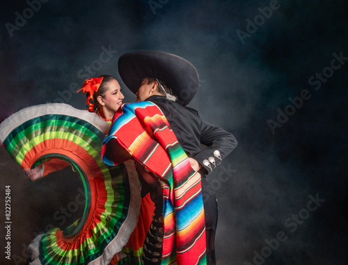 Latin Mexican couple with Jalisco, charro costumes A man and woman in traditional Mexican clothing are dancing together