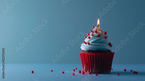 Blue cupcake with red sprinkles and lit candle on a blue background : Generative AI