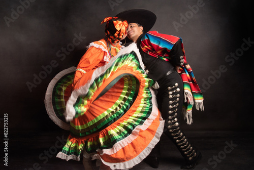 Latin Mexican couple with Jalisco, charro costumes A man and woman in traditional Mexican clothing are dancing together