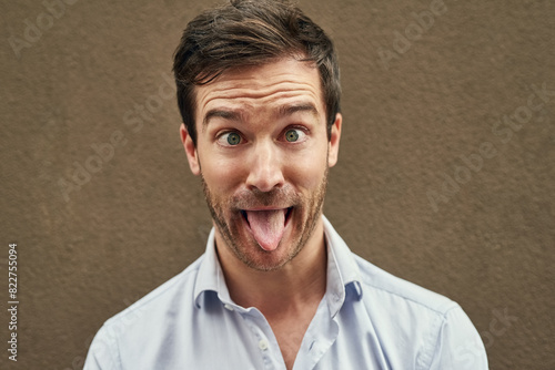 Photos Man, tongue and funny face on isolated background in silly, goofy or comedy on mockup or wall backdrop