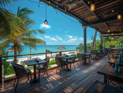 A beachfront restaurant with tables and chairs overlooking the ocean. The tables are set with umbrellas and there are several chairs around them. The atmosphere is relaxed and inviting