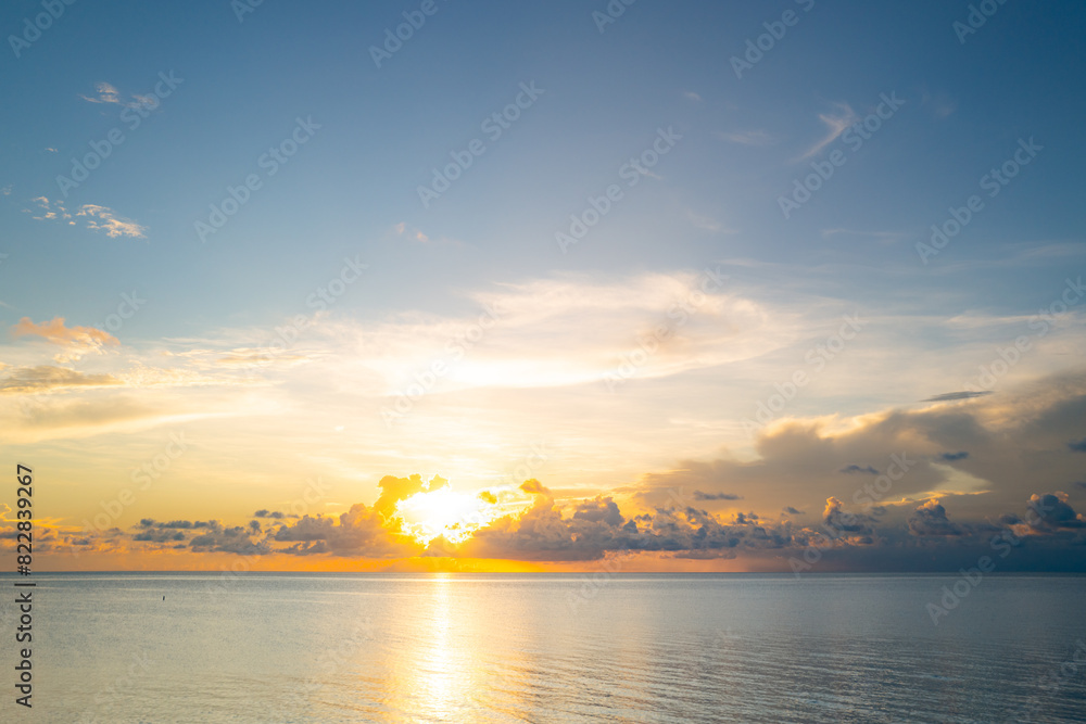 Sunset on tropical beach sea ocean with sunrise clouds. Banner for travel vacation. Scenery sky and reflection rays in water. Dusk, twilight on sea. Tranquil, golden sky background.