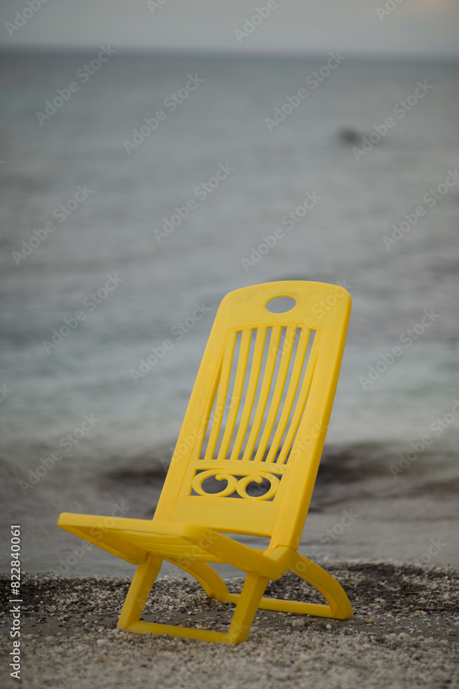Naklejka premium yellow chair on the beach