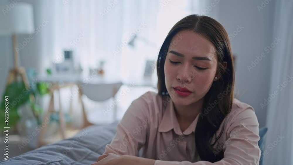 Asian upset depressed woman sitting alone on sofa in living room at home. Asian upset depressed woman sitting alone on sofa in living room at home.