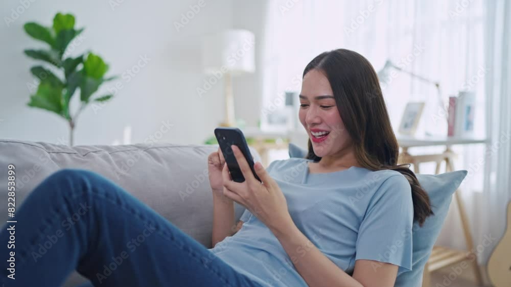 Asian beautiful woman sitting on sofa and swipe mobile phone in house. Asian beautiful woman sitting on sofa and swipe mobile phone in house.