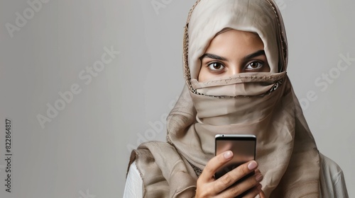 Close up of a veiled Islamic woman using a smartphone with blank background. photo